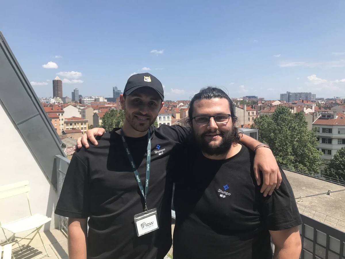 Deux membres de l'équipe SHUNPO posant sur un toit-terrasse, avec les toits de Lyon derrière eux.