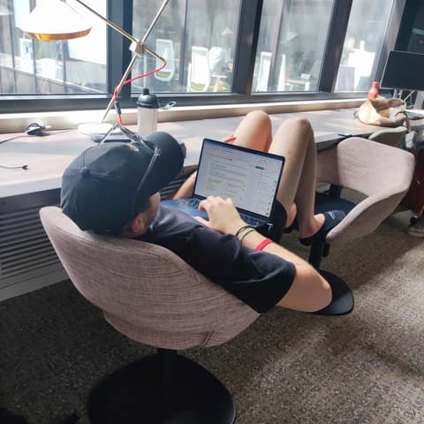 Un membre de l'équipe SHUNPO travaillant sur son ordinateur, renversé dans un fauteuil près d'une grande fenêtre.