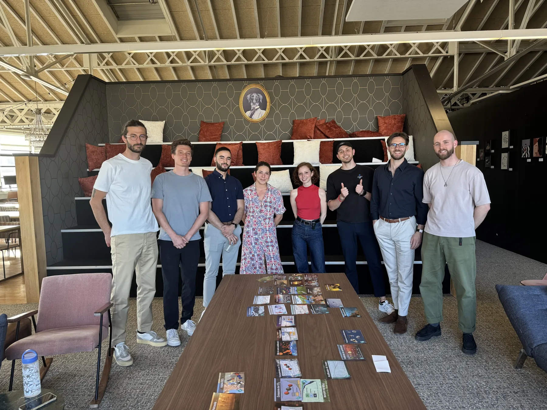 L'équipe SHUNPO debout autour d'une longue table couverte de cartes, dans une salle aux grandes poutres.