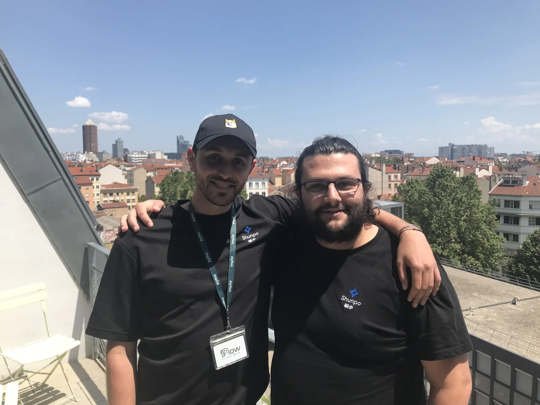 Deux membres de l'équipe SHUNPO posant sur un toit-terrasse, avec les toits de Lyon derrière eux.
